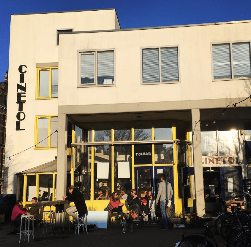 The best bars in Amsterdam | the lively exterior at Tolbar, bathed in warm light