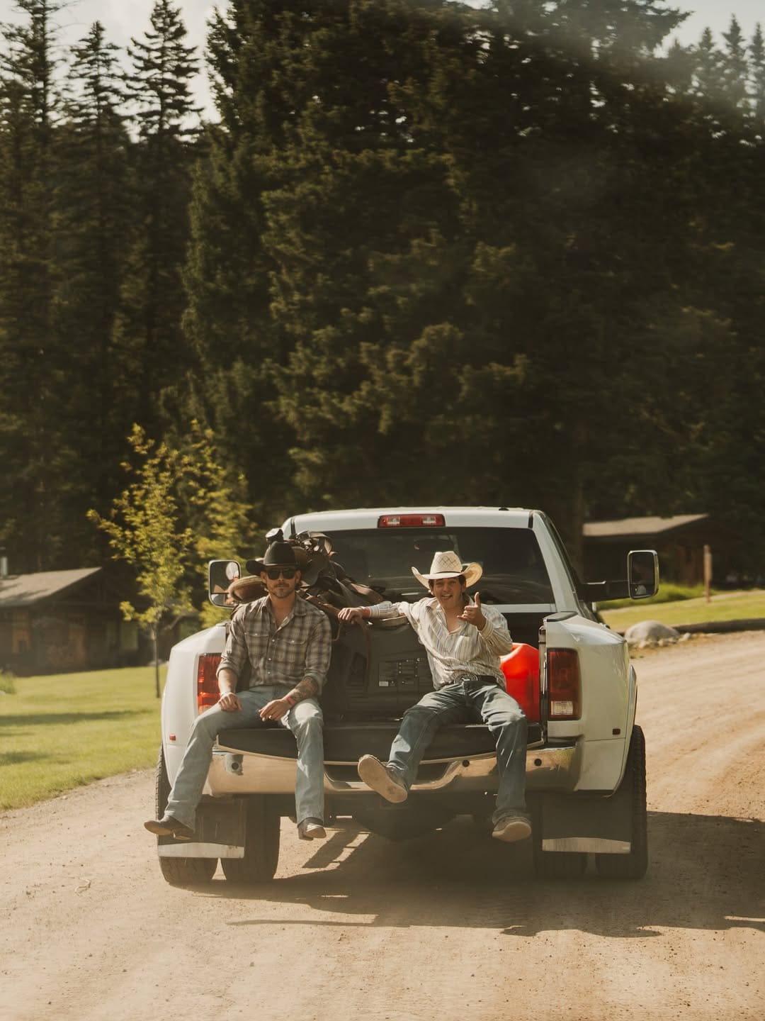 Two cowboys sitting on the back of a truck at Lone Mountain Ranch