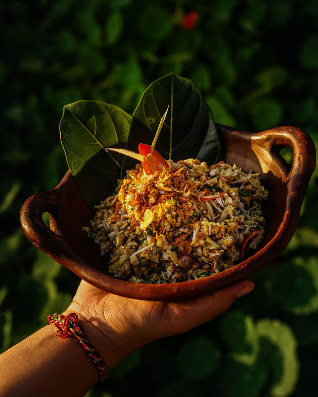 Hand holding local dish at Munduk Moding Plantation, a luxury eco-resort in Bali, Indonesia