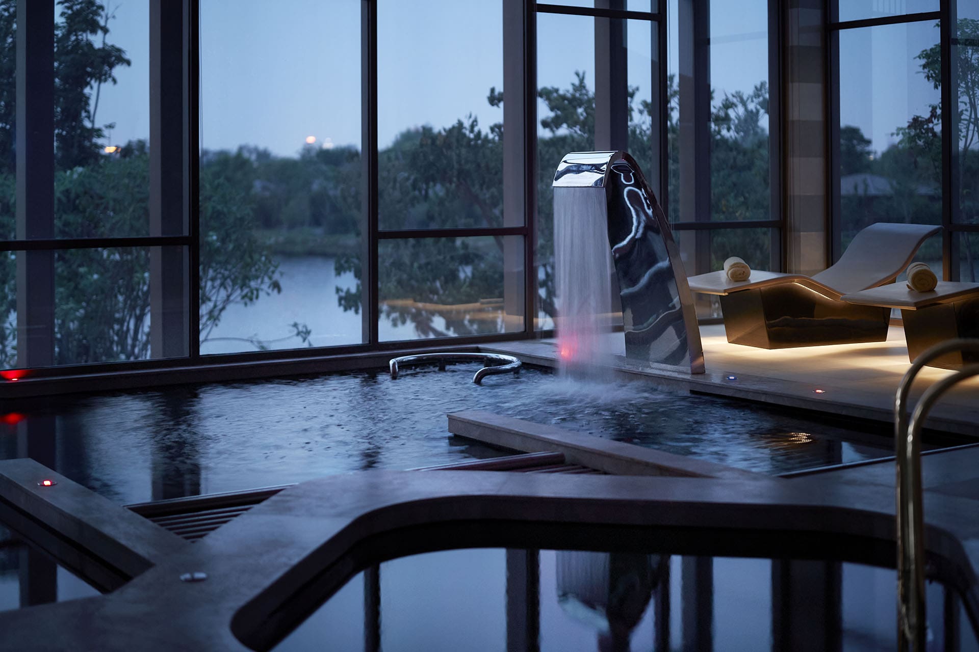 The hydrotherapy pool with window view of lake and trees at RAKxa, Thailand, a retreat dedicated to wellness