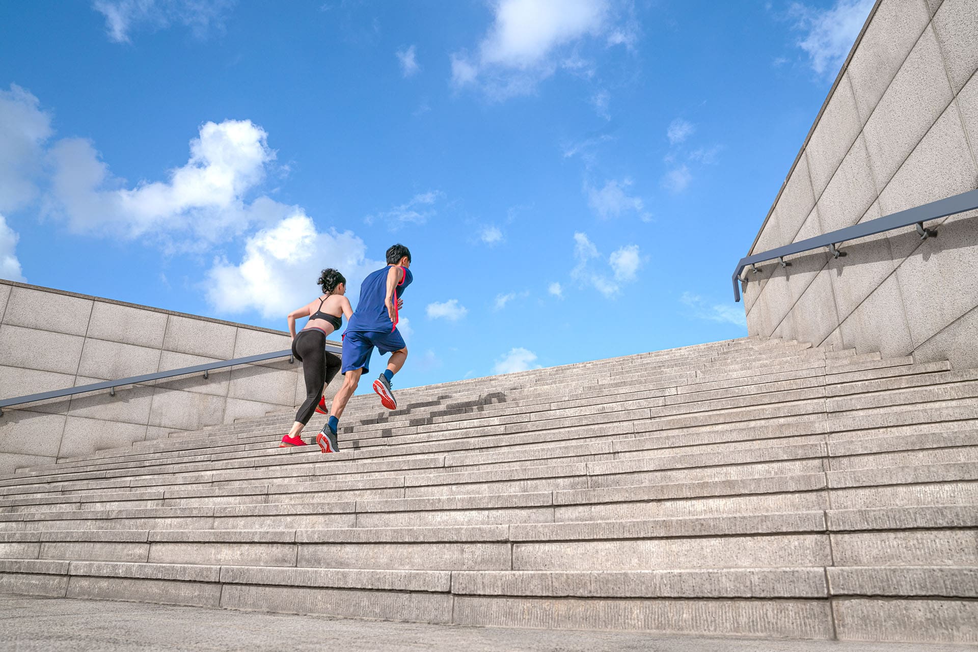 Fitness focused woman and man running up outside stairs at Westin hotel