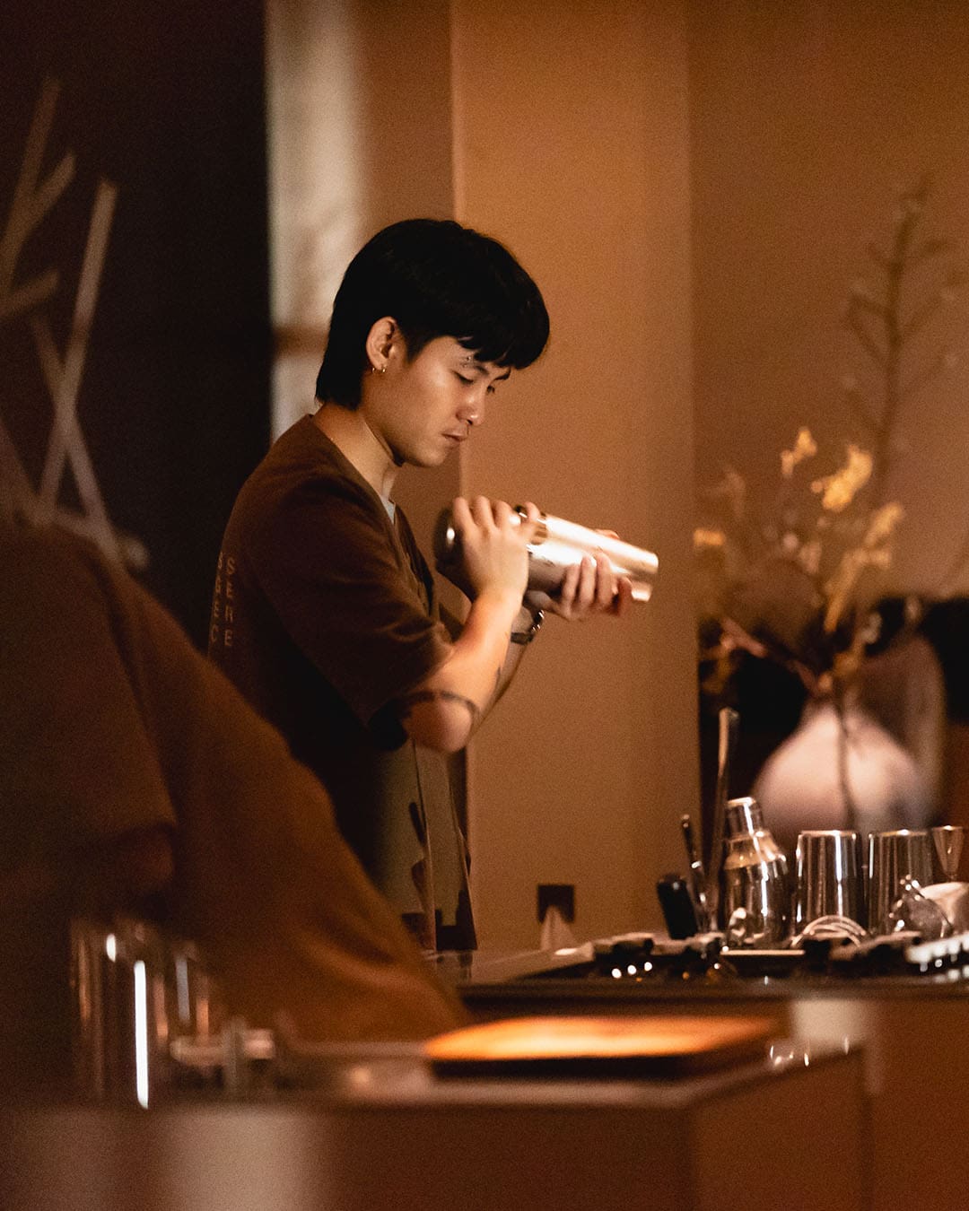 A waiter works on a cocktail at Messenger Service, a bar within Baan Trok