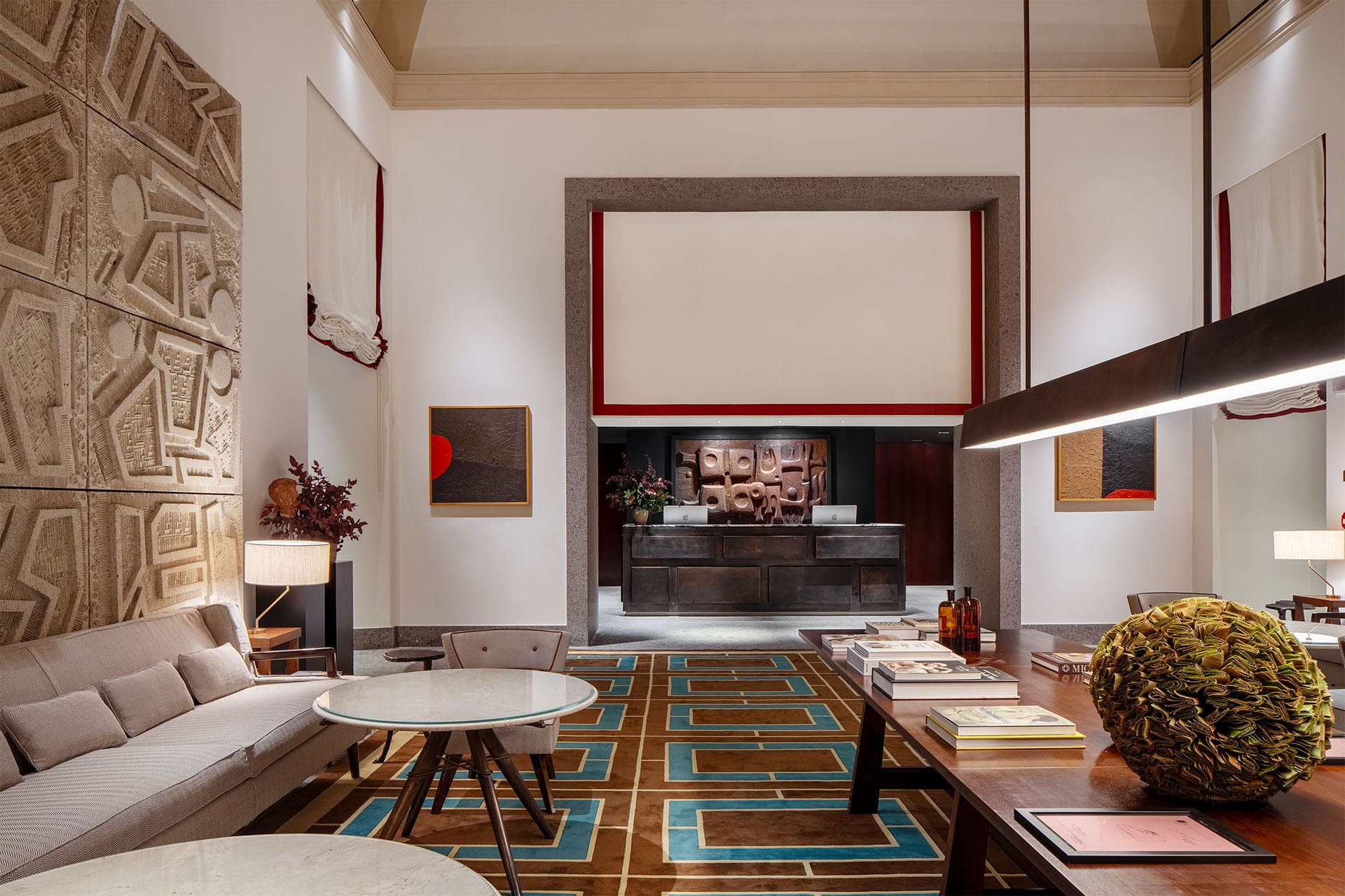 A graphic carpet and carved wall art within the striking reception of Portrait Milano