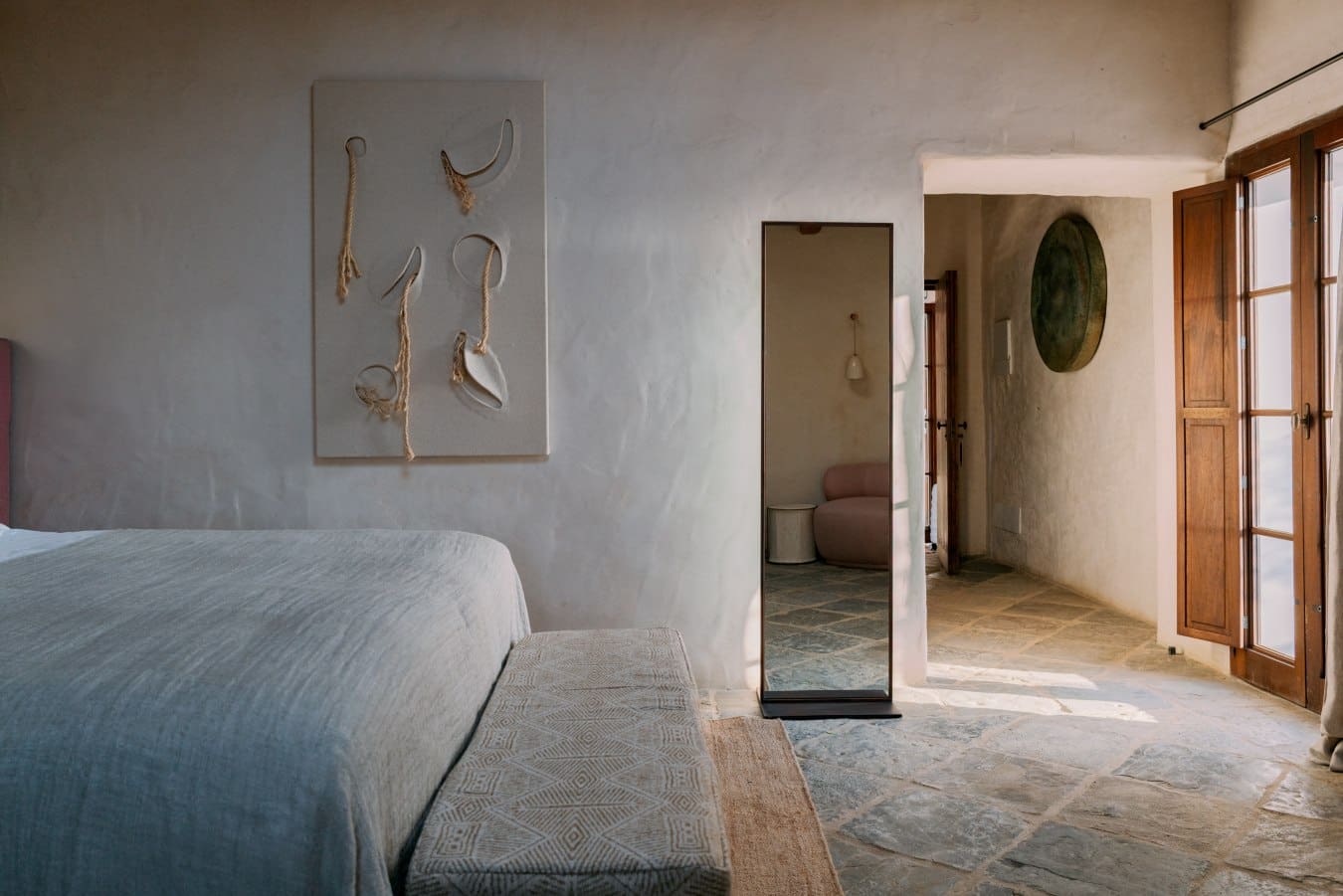 A bedroom at Son Ermità in neutral soothing tones, with a stone floor in view