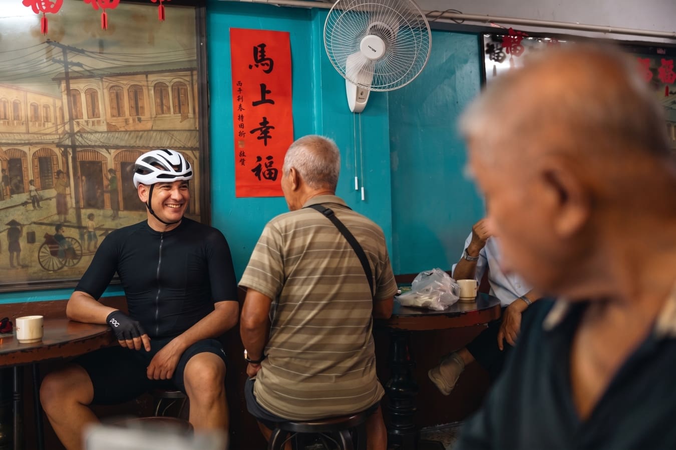 A man in a cycling helmet in a Bangkok cafe