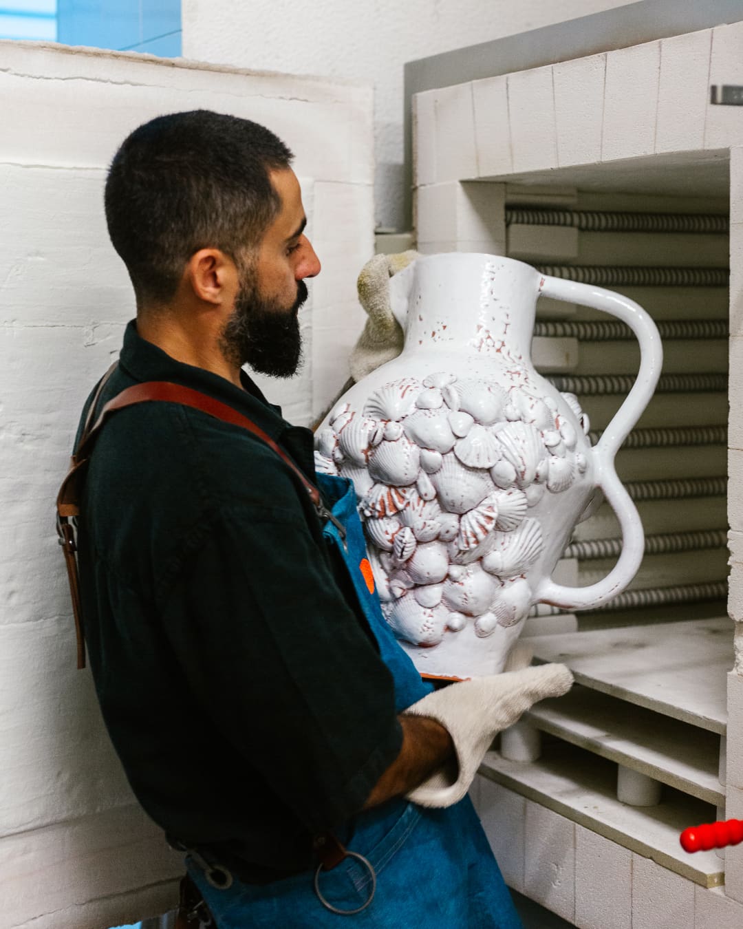 José Aparício Gonçalves holding a large ceramic vase coming out the kiln