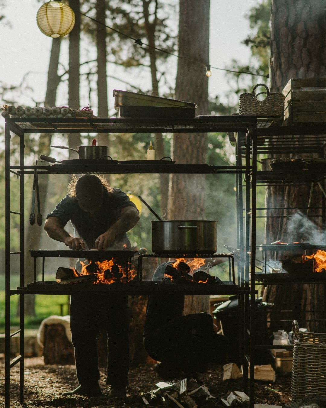 A man cooking over coals at The Dell of Abernethy in the Scottish Highlands