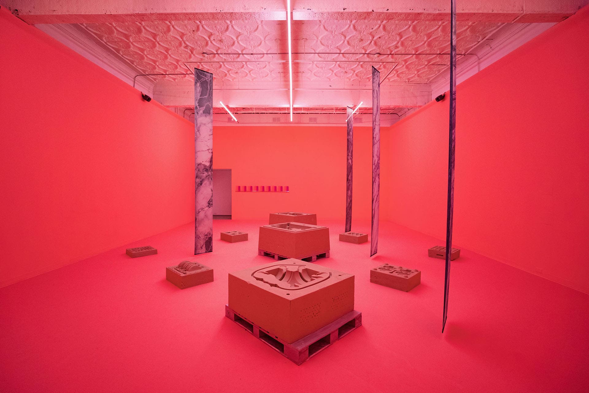 Artworks on display in a red room at Mercer Union